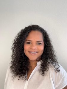 Photo Steffi com cabelos encaracolados no ombro e blusa branca